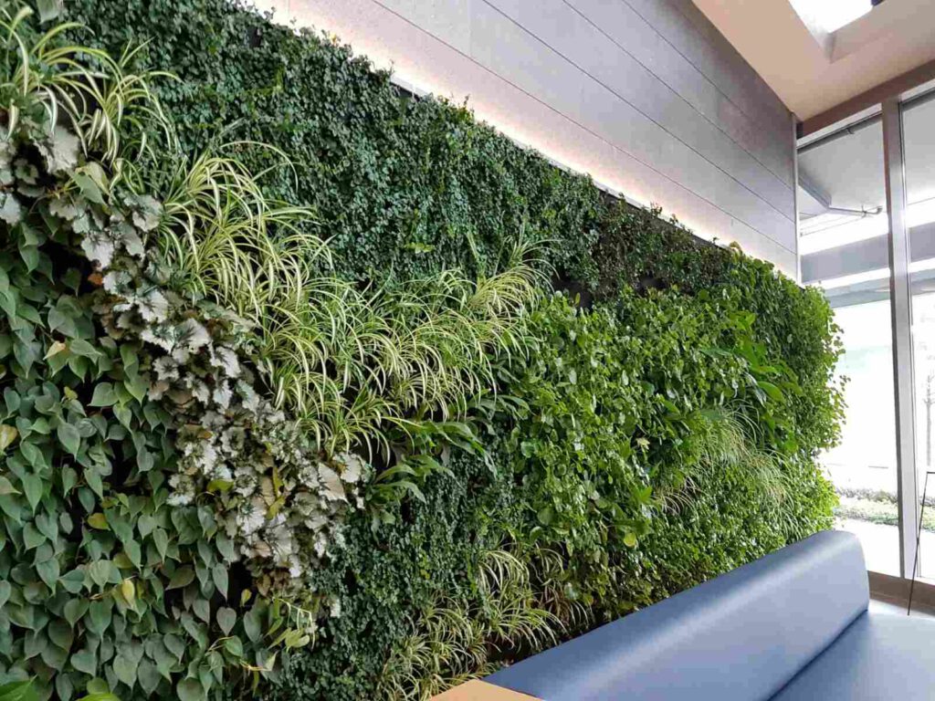 Jardín vertical de plantas artificiales cubriendo una pared interior iluminada