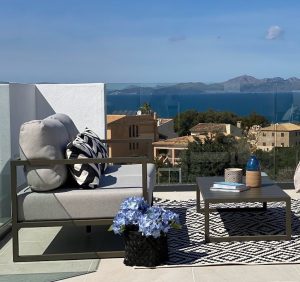Terraza con sofá gris y hortensias azules frente al mar, proyecto de interiorismo mediterráneo en Mallorca