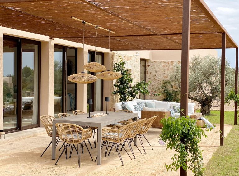 Porche con pérgola de cañizo, sillas de ratán y olivo en una reforma de vivienda en Mallorca