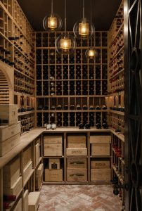 Bodega climatizada con botelleros de madera y suelo de barro, interiorismo a medida en Mallorca
