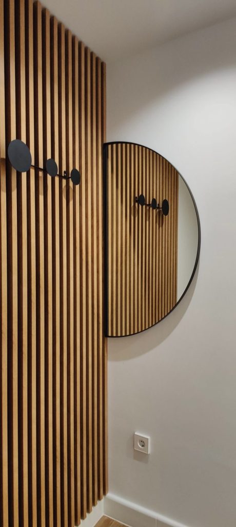 Detalle de pared de listones de madera con colgadores en el piso de Madrid