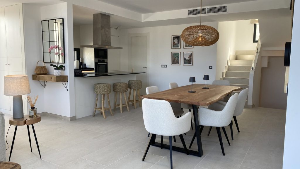 Cocina comedor en Colònia de Sant Pere, Mallorca, con mesa de madera natural, sillas blancas y lámpara de ratán
