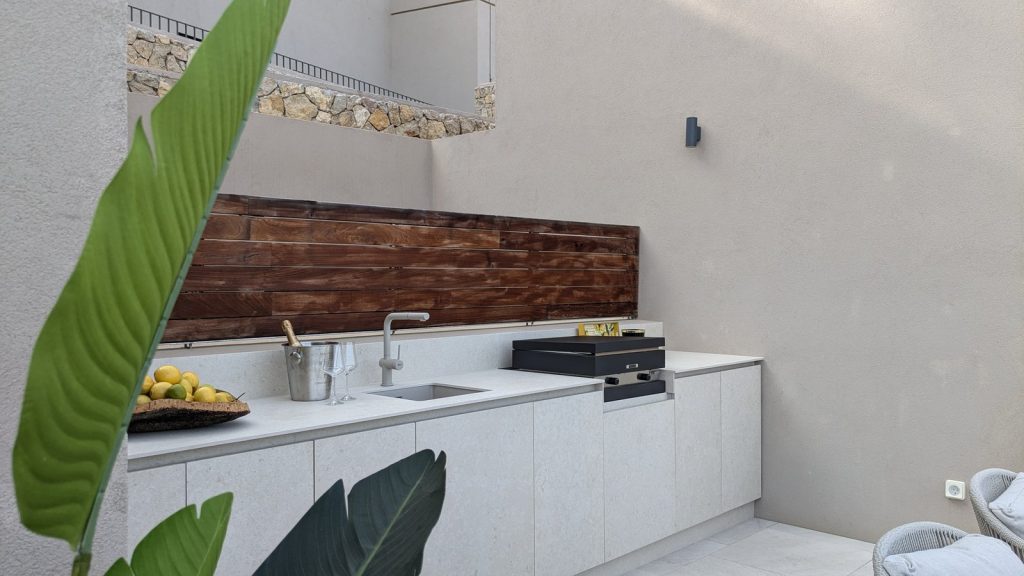 Detalle de cocina de verano en Puerto Andratx, Mallorca, con fregadero, plancha encastrada y frutero con limones