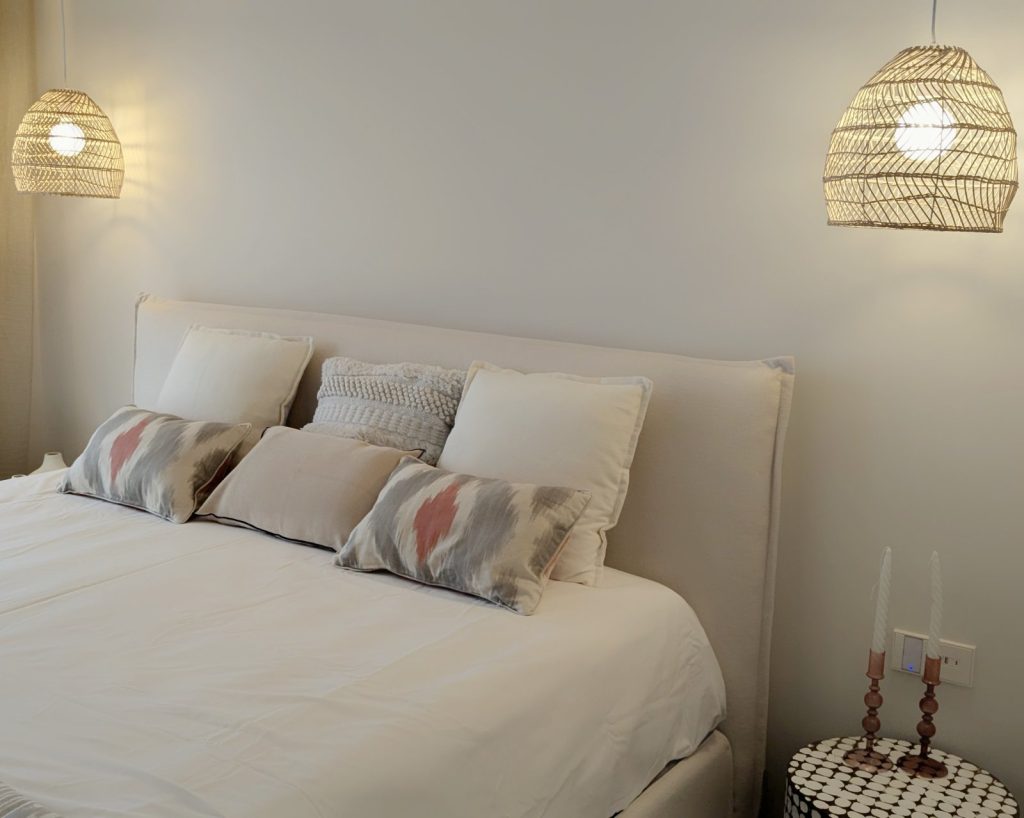 Dormitorio decorado en Puerto Andratx, Mallorca, con lámparas colgantes de ratán y cojines en tonos suaves