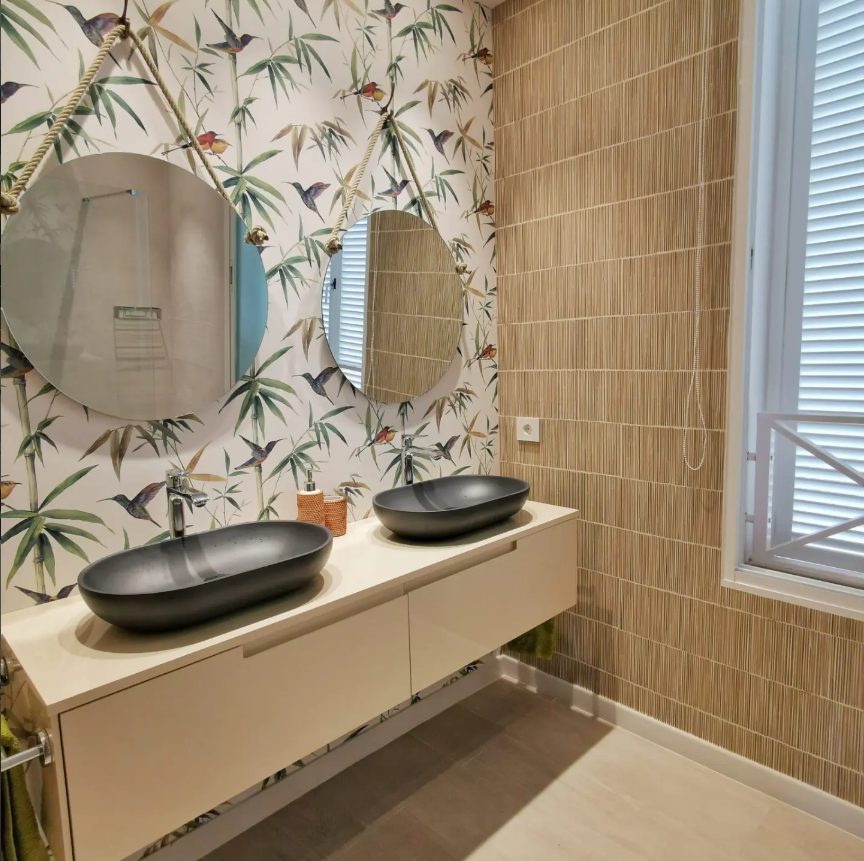 Bano con lavabos negros y papel pintado botanico en el apartamento de Magaluf
