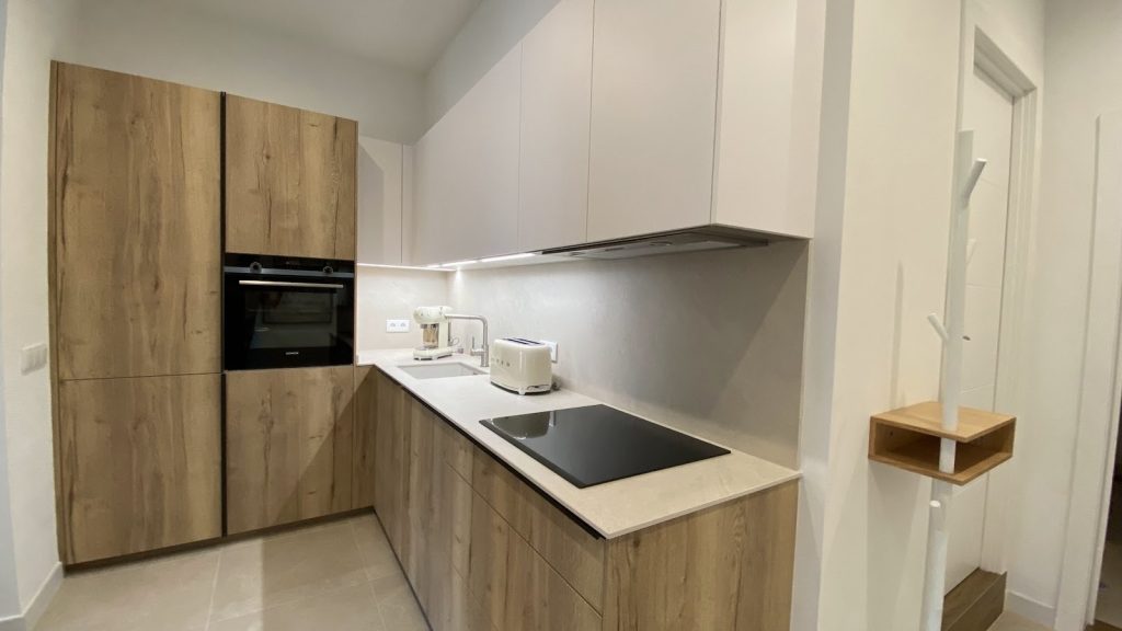 Cocina en blanco y madera clara tras la reforma de un piso en la plaza del Banc de l'Oli, Palma