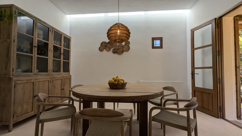 Comedor con mesa redonda de madera y lámpara de ratán en una casa payesa de Ibiza
