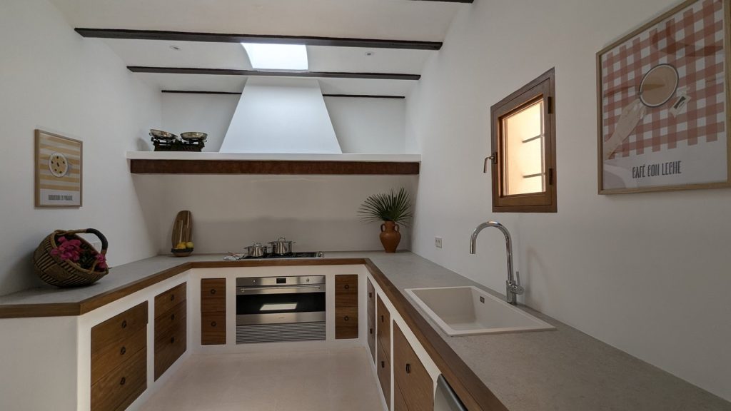 Cocina de obra con campana tradicional y frentes de madera en una finca de Ibiza