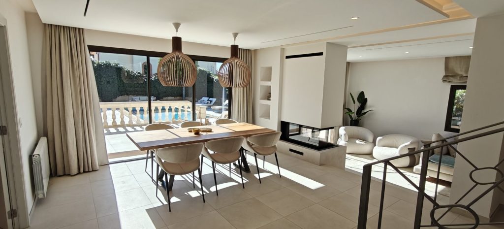 Comedor con chimenea de doble cara y vistas a la piscina en una casa de Marratxí, Mallorca