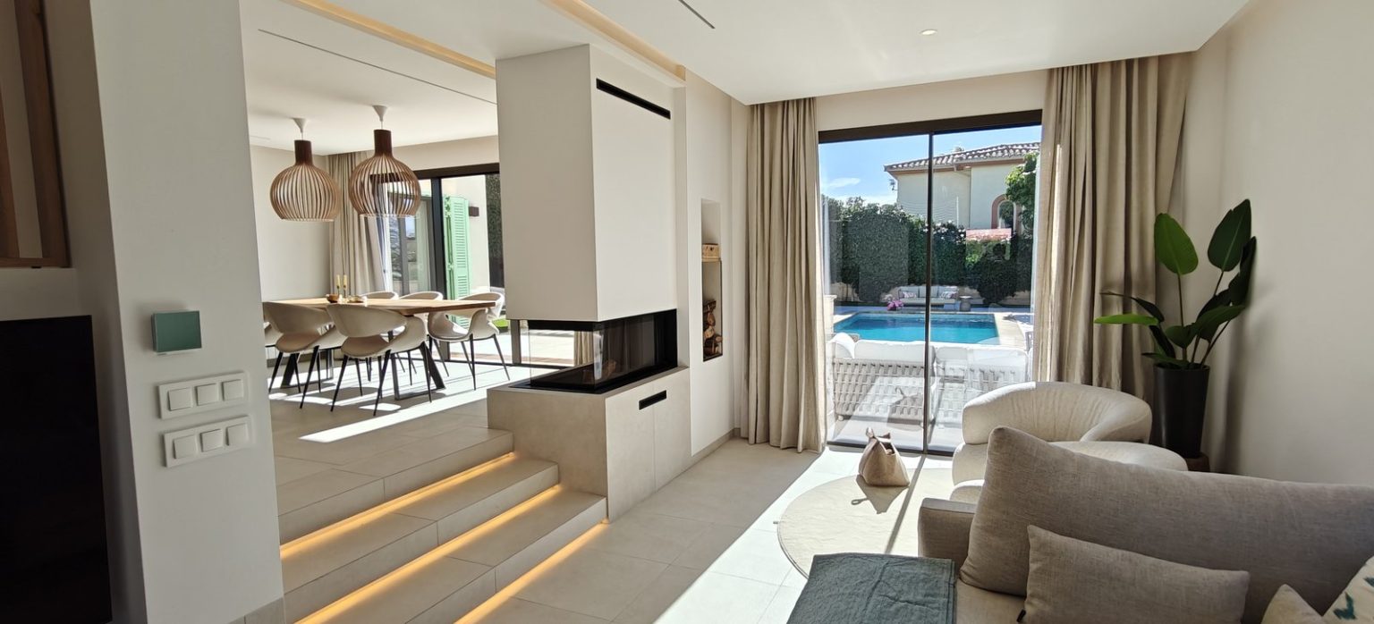 Salón con chimenea panorámica y salida al jardín con piscina en Marratxí, Mallorca