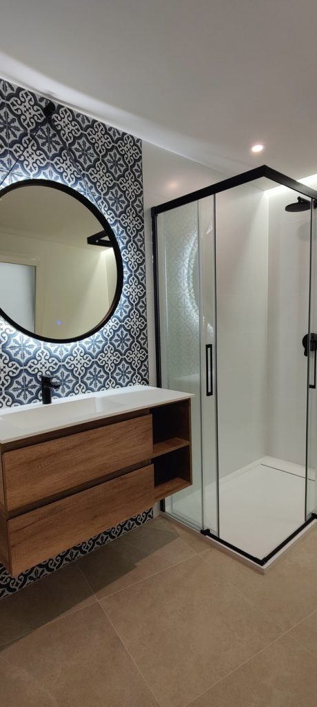 Mueble de lavabo de madera y espejo retroiluminado en un baño reformado en Palma de Mallorca