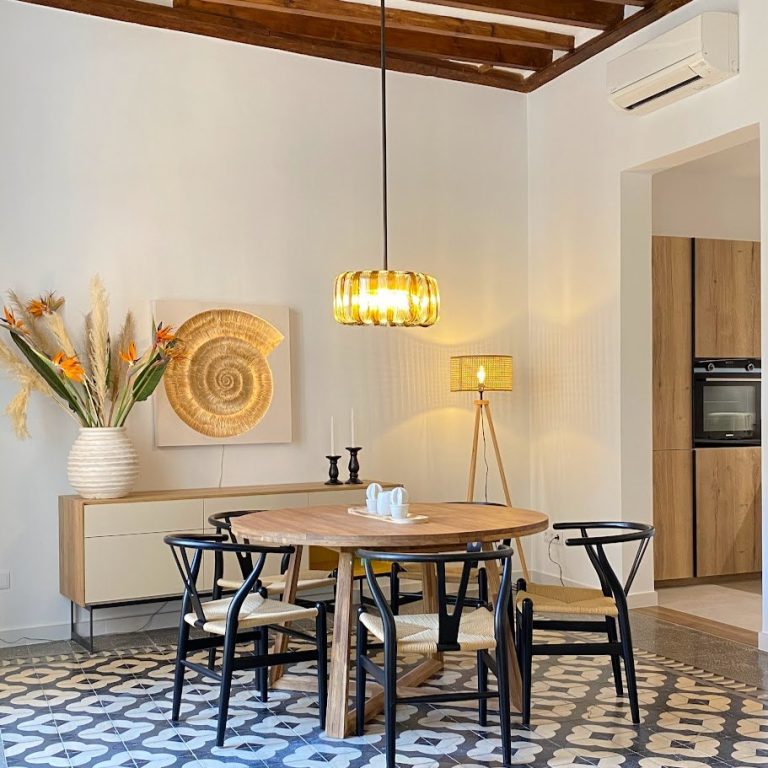 Comedor con mesa redonda de madera y sillas negras en un piso reformado del centro de Palma